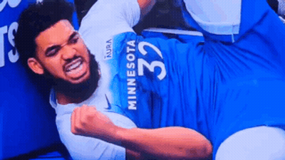 A Man In A Minnesota Jersey Is Laying On The Floor With His Fist In The Air . GIF