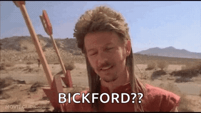 A Man In A Mullet Is Holding A Bow And Arrow In The Desert And Says Bickford ? GIF