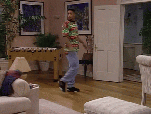 A Man In A Multicolored Shirt Is Dancing In A Living Room GIF