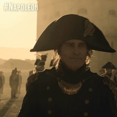 A Man In A Napoleon Hat Is Standing In Front Of A Building GIF