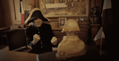 A Man In A Napoleon Hat Sitting At A Desk GIF
