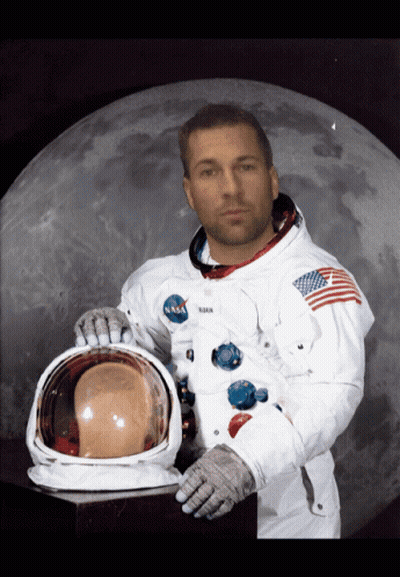 A Man In A Nasa Space Suit Holds His Helmet In Front Of A Full Moon GIF