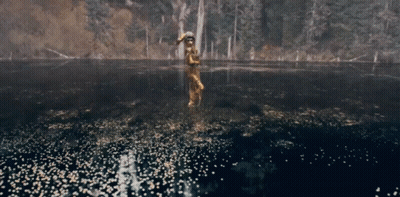 A Man In A Native American Outfit Is Standing In A Lake GIF