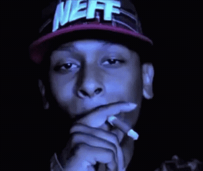 A Man In A Neff Hat Is Smoking A Cigarette . GIF