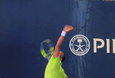A Man In A Neon Green Shirt Is Playing Tennis GIF