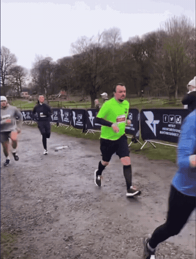 A Man In A Neon Green Shirt Is Running In Front Of A Banner That Says #Test GIF