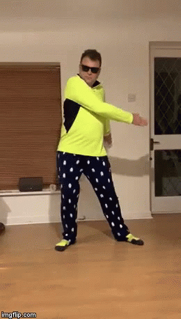 A Man In A Neon Yellow Shirt And Blue Polka Dot Pants Is Dancing In A Living Room GIF