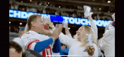 A Man In A New York Giants Jersey Is Giving A High Five To A Woman GIF