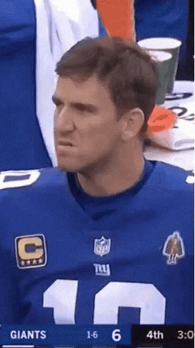 A Man In A New York Giants Jersey Is Watching A Football Game GIF