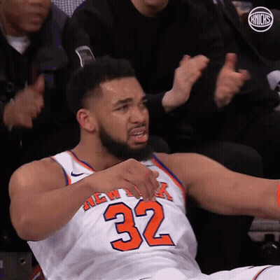 A Man In A New York Knicks Jersey Is Sitting On The Floor GIF