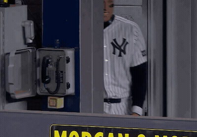 A Man In A New York Yankees Uniform Stands In Front Of A Phone Box GIF