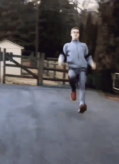 A Man In A Nike Jacket Is Running On A Road GIF
