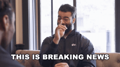 A Man In A Nike Jacket Laughs With The Words " This Is Breaking News " Behind Him GIF