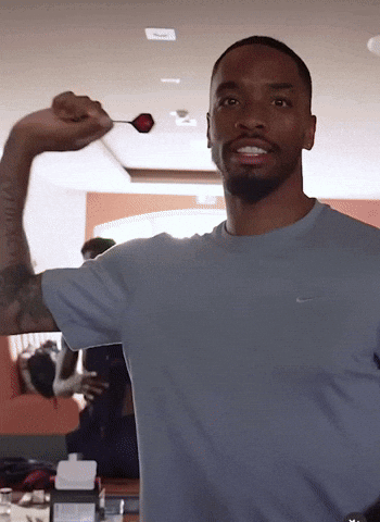 A Man In A Nike Shirt Is Holding A Dart GIF