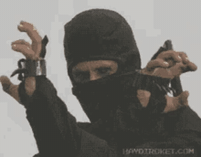 A Man In A Ninja Mask Is Holding A Gun In His Hand GIF