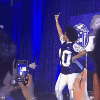A Man In A Number 10 Jersey Is Dancing On Stage GIF