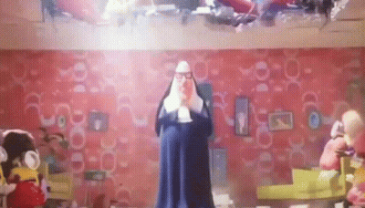 A Man In A Nun Costume Is Standing In A Room With Stuffed Animals . GIF