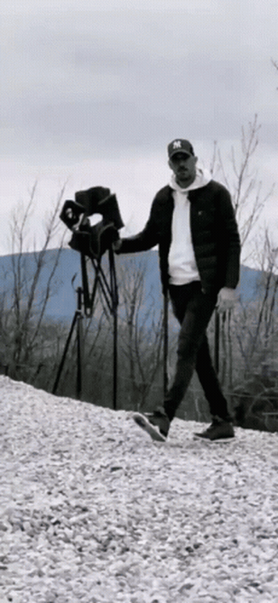 A Man In A Ny Hat Is Walking On A Pile Of Gravel . GIF
