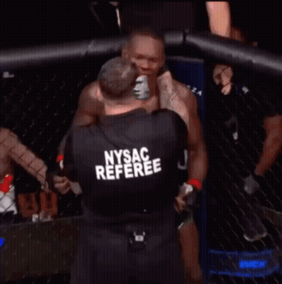 A Man In A Nysac Referee Shirt Stands In Front Of A Cage GIF