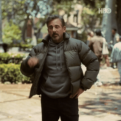 A Man In A Padded Jacket Is Standing On A Sidewalk In Front Of A Sign That Says Hbo GIF