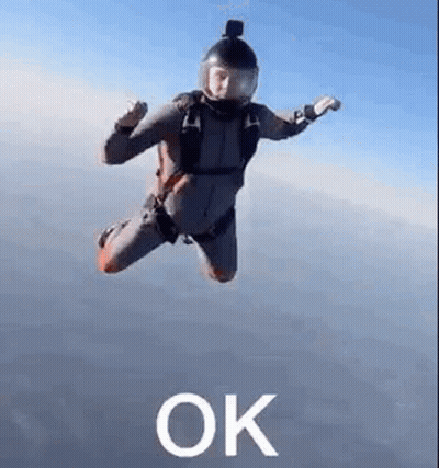 A Man In A Parachute Suit Is Flying Through The Air With The Word Ok . GIF