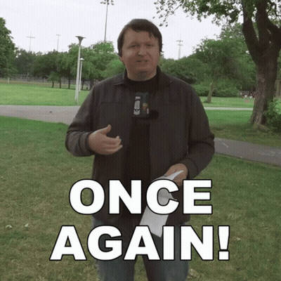 A Man In A Park Holding A Piece Of Paper That Says Once Again On It GIF