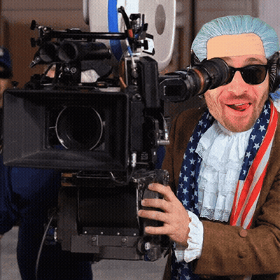 A Man In A Patriotic Costume Is Holding A Camera And Smiling GIF