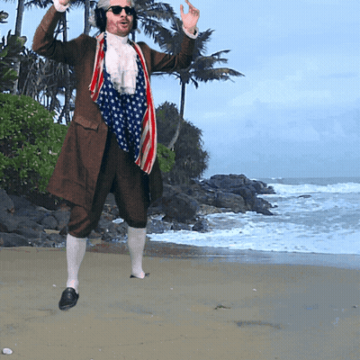 A Man In A Patriotic Outfit Is Standing On A Beach GIF