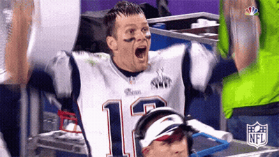 A Man In A Patriots Jersey Is Celebrating With His Arms In The Air And His Mouth Open . GIF