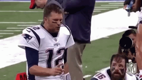 A Man In A Patriots Jersey Is Standing On A Football Field With Another Man . GIF
