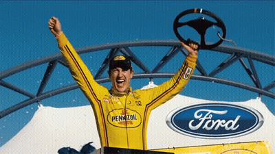 A Man In A Pennzoil Shirt Holds A Steering Wheel In His Hand GIF