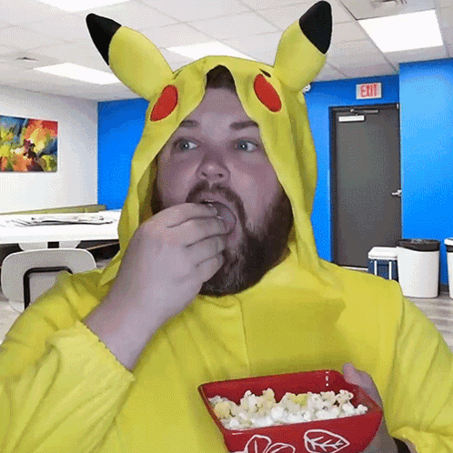 A Man In A Pikachu Costume Is Eating Popcorn In Front Of An Exit Sign GIF