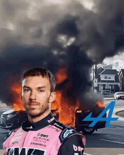 A Man In A Pink Alpine Racing Suit Is Standing In Front Of A Car On Fire GIF