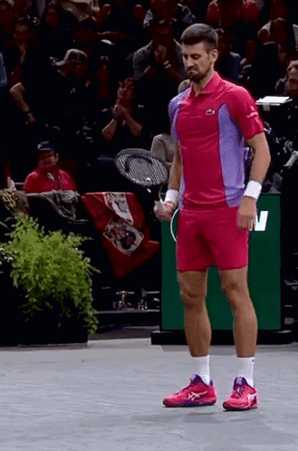 A Man In A Pink And Purple Shirt Holds A Tennis Racquet GIF