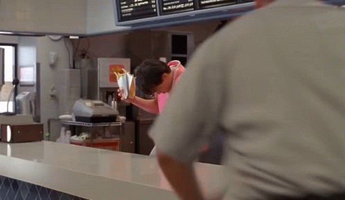 A Man In A Pink Apron Pours Milk Into A Cup GIF