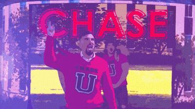 A Man In A Pink Chase U Sweater Stands In Front Of A Chase Sign GIF