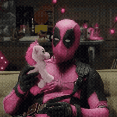 A Man In A Pink Deadpool Costume Is Holding A Pink Unicorn GIF