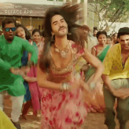 A Man In A Pink Dress Is Dancing With A Group Of People . GIF