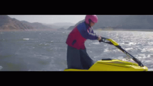 A Man In A Pink Helmet Is Riding A Jet Ski GIF
