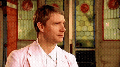 A Man In A Pink Jacket And White Shirt Is Standing In Front Of A Stained Glass Door . GIF