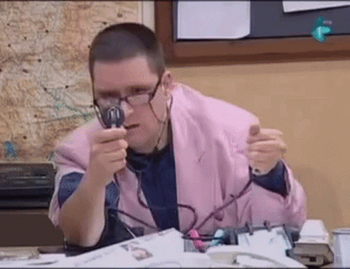 A Man In A Pink Jacket Is Holding A Magnifying Glass In Front Of His Face . GIF