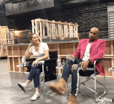 A Man In A Pink Jacket Sits Next To A Woman In A Chair GIF