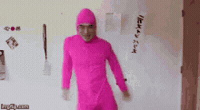 A Man In A Pink Jumpsuit Is Standing In Front Of A Refrigerator . GIF