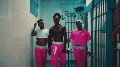 A Man In A Pink Prison Uniform Is Walking With Two Other Men GIF
