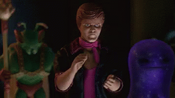 A Man In A Pink Scarf Is Standing In Front Of A Purple Ghost . GIF