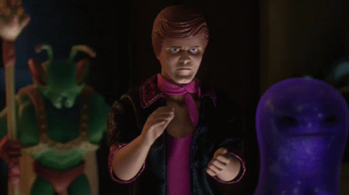 A Man In A Pink Scarf Stands In Front Of A Purple Monster GIF