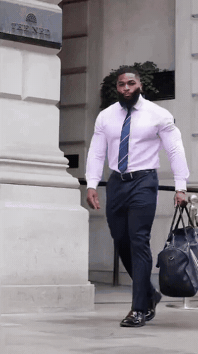 A Man In A Pink Shirt And Tie Is Carrying A Black Bag GIF