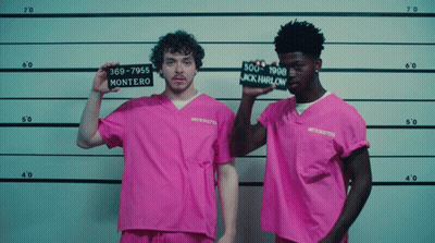 A Man In A Pink Shirt Holds Up A Sign That Says " Montero " GIF