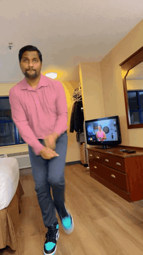 A Man In A Pink Shirt Is Dancing In A Room GIF