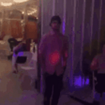 A Man In A Pink Shirt Is Dancing On A Dance Floor In A Room . GIF